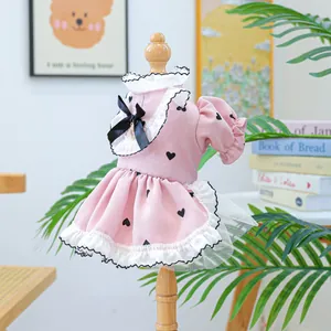 Dettaglio dell'abito rosa per animali con stampa a cuori, pizzo bianco e fiocco di raso