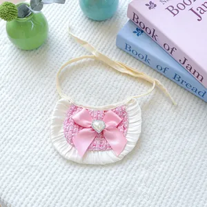 Detailed view of pink tweed pet bandana with satin bow and heart-shaped gemstone