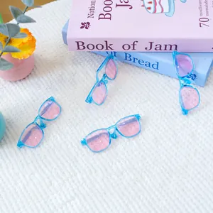 Set van vier mini poppenbrillen in hemelsblauw met roze lenzen op zachte witte stof
