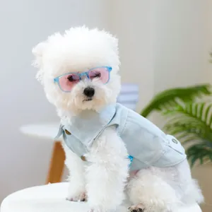 Detail van een denim hondenhestje met knopen en roze zonnebril op een witte hond