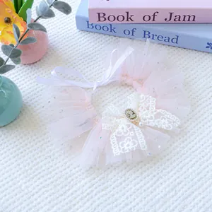Détail d'un bavoir rose pour animaux avec dentelle, tulle brillant et broche vintage