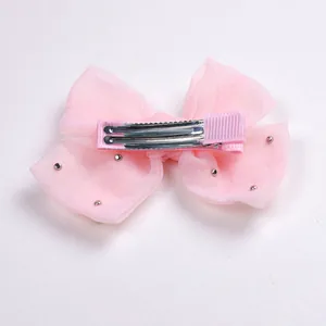 Détail arrière du nœud en organza rose avec perles argentées et pince crocodile
