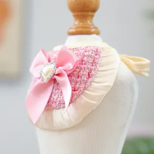 Close-up of pink tweed pet bandana featuring a satin bow with heart pearl and rhinestone