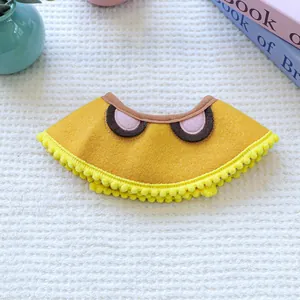 Detail of yellow pet bib with cartoon eyes and soft pom-poms on waffle fabric