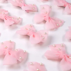 Gros plan de nœuds en organza rose clair pour animaux avec perles blanches élégantes