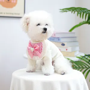 Close-up of pink tweed pet bandana with lace trim and heart rhinestone bow on white knit