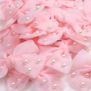 Détail de barrettes nœuds en tulle rose avec perles et pince en métal pour chiens