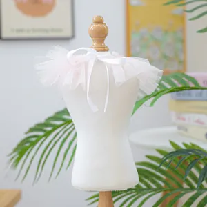 Détail d'un bavoir rose en tulle avec des volants en dentelle et un nœud en ruban blanc
