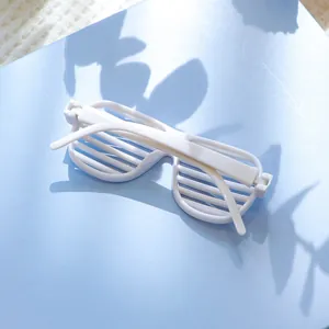 Detailopname van witte shutterbril voor huisdieren op blauwe achtergrond met bladschaduw
