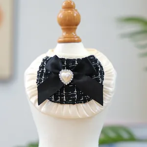 Detail of tweed pet bib with satin pleats, black bow, and heart pearl centerpiece