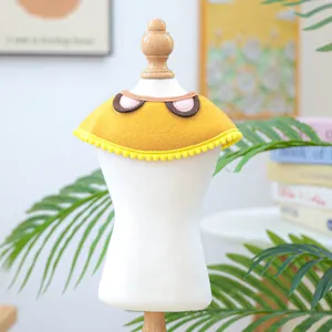 Close-up of a yellow felt pet collar with soft pom-poms and cartoon eye details