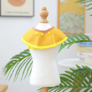 Detail of yellow pet shawl with pom-pom trim and decorative buttons on mini mannequin