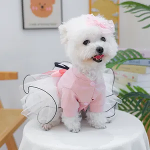 Détail d'un cardigan rose pour animal et d'une jupe en tulle blanc avec nœud en perles