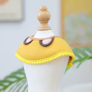 Detail of yellow pet bib with pink round patches and yellow pom-pom trim on model