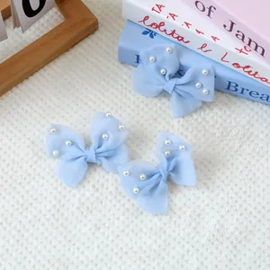 Lot de trois barrettes à nœuds en tulle bleu clair avec perles sur fond de fourrure blanche