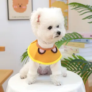 Close-up of a white pet sweater and a yellow bib with pom-poms on a small dog
