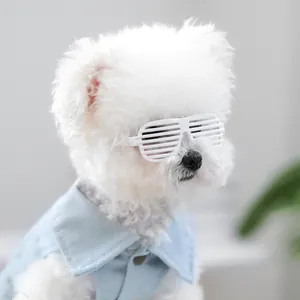 Detailopname van een kleine witte hond met witte shutter-bril en blauw denim vest