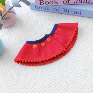 Detail of red pet bib with soft velvet fabric and decorative red pom-poms on white background