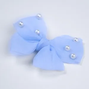 Gros plan du nœud papillon en mousseline bleu clair avec perles blanches pour petit chien