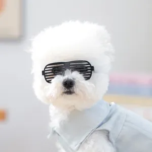 Macro-opname van een witte hond met zwarte shutterbril en een blauw katoenen shirt