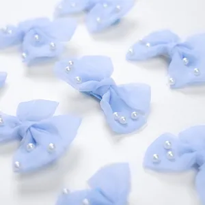 Détail de barrettes nœuds en tulle bleu clair avec perles blanches pour petits animaux
