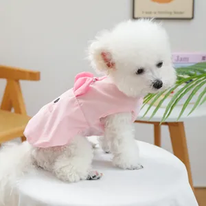 Detail van roze hondenjurk met 3D-strik en borduursel op een kleine witte hond