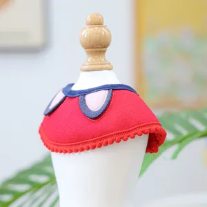 Close-up of cute red pet bib with pink ears and fuzzy pompom trim on white display stand