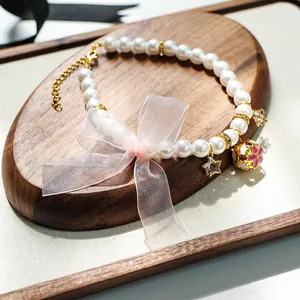 Détail du collier de perles pour animaux avec nœud en organza rose et clochette fleurie
