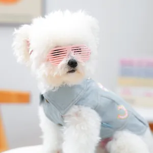 Macro-opname van een witte puppy met een lichtblauw denim vest en roze shutterbril