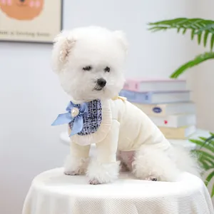 Close-up of dog bib featuring blue tweed fabric, satin bow, and heart pearl button