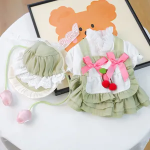 Détail de robe verte pour petit chien avec bordure en dentelle, nœuds roses et cerises