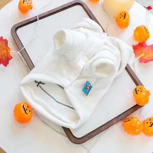 Close-up of a white textured knit pet vest with round buttons on a wooden tray