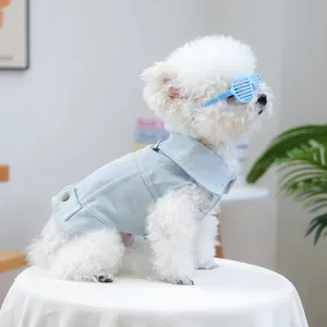 Detail van een witte hond met een lichtblauw denim vest en blauwe shutter zonnebril