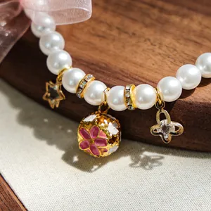 Détail d'un collier de perles pour animaux avec papillon en cristal et nœud en tulle