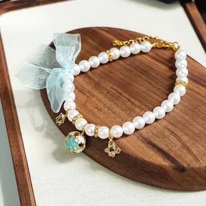 Détail du collier de perles pour animaux avec nœud en organza bleu et sphère florale