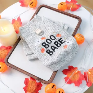 Detail of grey knitted pet vest with Halloween pumpkin embroidery and metal leash D-ring