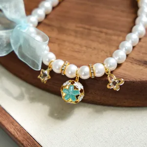 Détail du collier de perles pour animaux avec breloques étoiles et un nœud en soie bleu