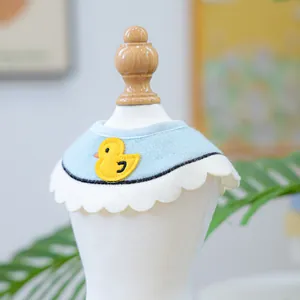 Detailed view of light blue pet bandana with yellow duck embroidery and white scallop edges