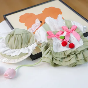 Détail de robe pour animal avec cerises, nœuds roses et dentelle sur tissu à carreaux
