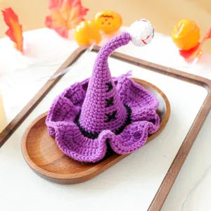 Détail d'un chapeau de sorcier violet tricoté pour animaux avec œil rouge sur plateau en bois