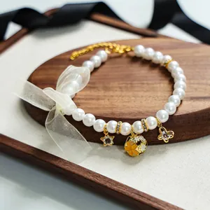 Détail du collier de perles pour animaux avec grand nœud et breloques dorées