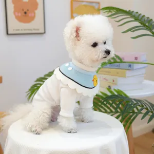 Close-up of white knitted pet sweater and blue bib with cute yellow chick embroidery
