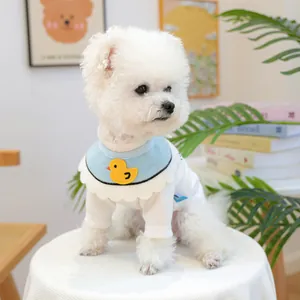 Close-up of a blue ruffled pet bib with a yellow duck embroidery on a white puppy