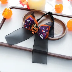 Détail du nœud d'Halloween pour animaux avec breloque citrouille, clochettes et fantômes