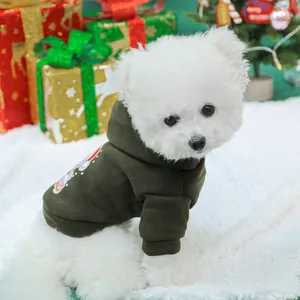 White dog wearing a warm dark green Christmas hoodie in a festive holiday scene