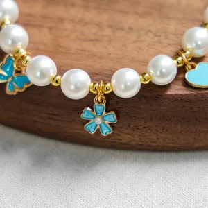 Détail du collier de perles pour animaux avec pendentifs papillon bleu et or