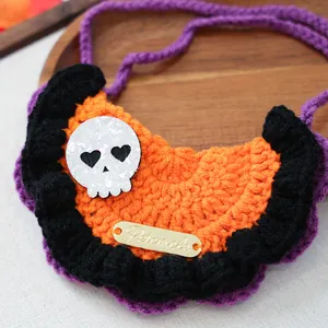Macro detail of hand-knitted Halloween pet collar with skull patch and gold metal tag