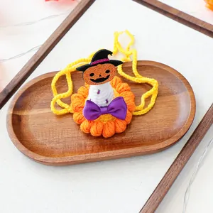 Détail d'un bavoir crocheté pour animaux avec citrouille d'Halloween et nœud violet