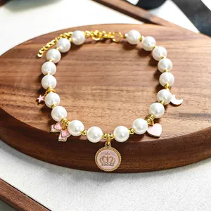 Détail de collier en perles pour animaux avec pendentifs émaillés roses et fermoir doré