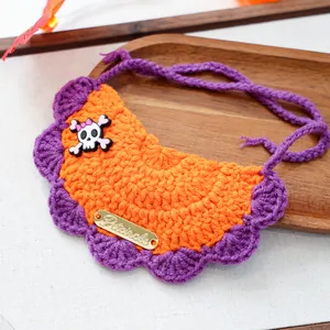 Close-up of hand-knitted orange and purple pet bib with a skull and bow detail